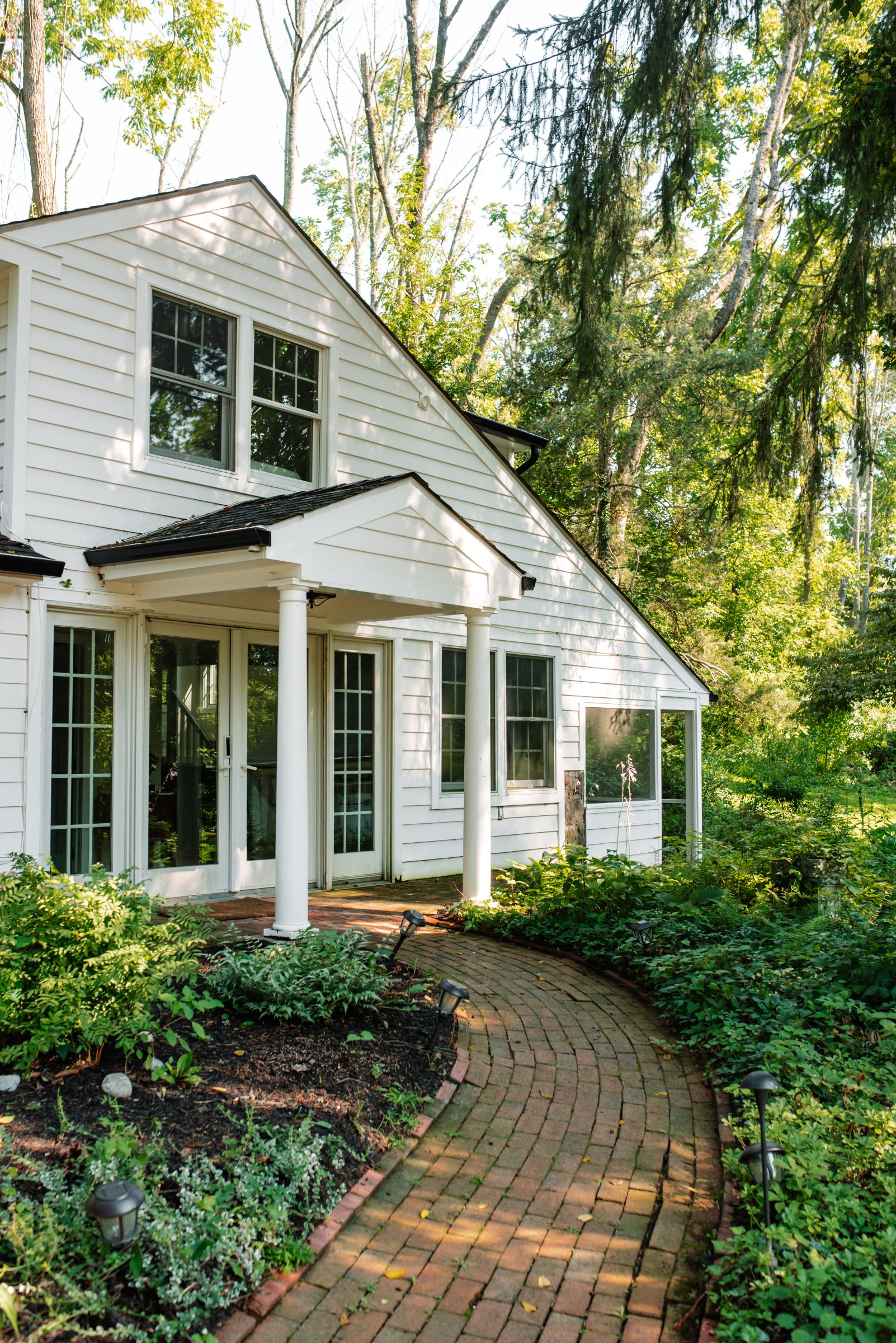 The white guest cottage with brick path and portico